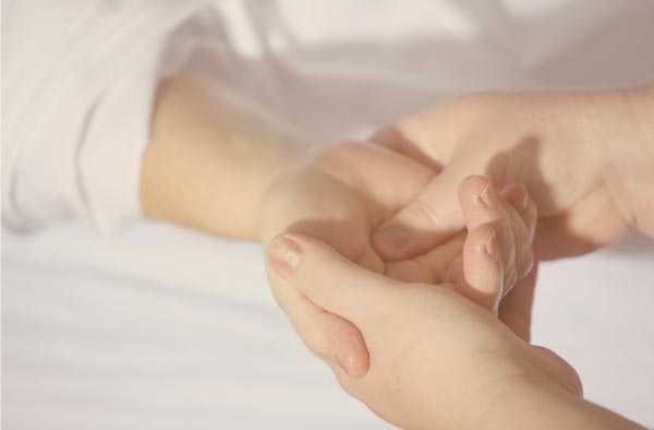 practitioner massaging client's palm